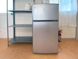 a refrigerator is standing next to a shelf at カモゲストハウス in Tsuruoka