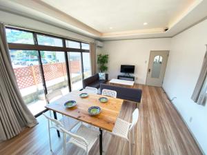 カモゲストハウス في تسوروكا: غرفة معيشة مع طاولة وكراسي خشبية