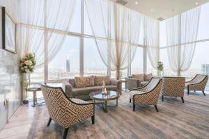 فندق غراند ماجستيك الكويت في الكويت: غرفة معيشة مع أريكة وكراسي ونوافذ كبيرة