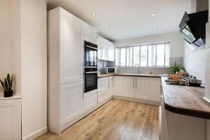 uma cozinha com armários brancos e piso em madeira em *Contractors, Holidays, Races, 25% off long stays* em Cheltenham