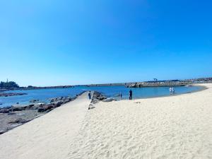 a beach with people walking on the sand and water at カモゲストハウス in Tsuruoka