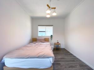 1 dormitorio con 1 cama en una habitación blanca en カモゲストハウス, en Tsuruoka