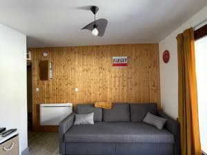 een woonkamer met een grijze bank voor een houten muur bij Appartement Huez, 2 pièces, 4 personnes - FR-1-405-25 in L'Alpe-d'Huez