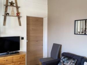 Appartement Huez, 3 pièces, 6 personnes - FR-1-405-229 في Huez: غرفة معيشة بها أريكة وتلفزيون