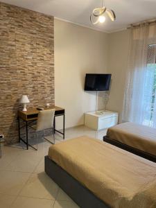 - une chambre avec 2 lits, un bureau et une télévision dans l'établissement CASAMAGNOLIA, à Cernusco sul Naviglio