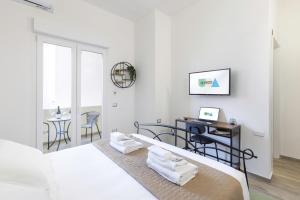 a white bedroom with a bed and a desk at Quarzo. Modern Rooms in Cagliari