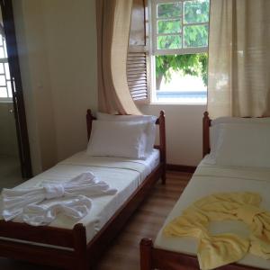 2 camas individuales en una habitación con ventana en Hotel POUSADA Brava, en Vila Nova Sintra