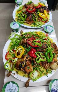 dos platos de comida en una mesa con pimientos y cebollas en Sail Alhasa Tourist Resort-Tafila, en Tufailah