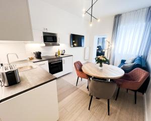 Apartment Düsseldorf City في دوسلدورف: مطبخ وغرفة معيشة مع طاولة وكراسي