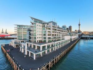 un grand bâtiment blanc sur l'eau avec un quai dans l'établissement Waterfront Seaview Hotel Apartment - same building block as Auckland Hilton, à Auckland