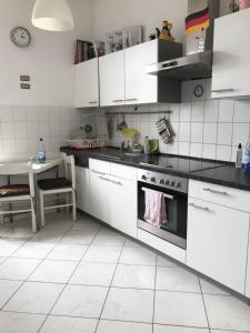 - une cuisine avec des placards blancs et une cuisinière dans l'établissement Privat Zimmer in Bad Homburg bei Kurhaus, à Bad Homburg vor der Höhe