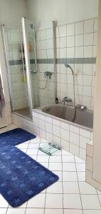 La salle de bains est pourvue d'une baignoire et d'un tapis bleu. dans l'établissement Privat Zimmer in Bad Homburg bei Kurhaus, à Bad Homburg vor der Höhe