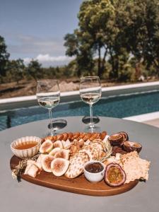 une assiette de nourriture et deux verres à vin sur une table dans l'établissement Suite do Meco, Refugio no meio da natureza, à Sesimbra