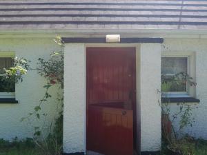 una puerta roja al lado de una casa en Longford Holiday Red Rose Self Catering Cottage, en Longford