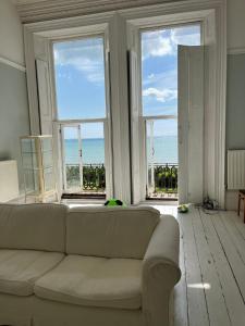 a living room with a couch and a view of the ocean at Stunning Period & Family Apartment by the Sea in St. Leonards