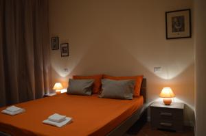 een slaapkamer met een oranje bed met 2 lampen bij La Casa di Rachele in Lucca