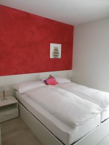 um quarto com uma cama branca e uma parede vermelha em B&B Tencia em Prato