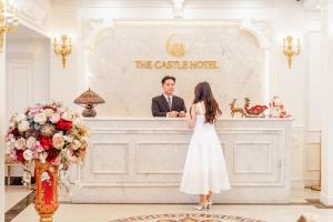 a bride and groom standing in front of the cashier at a wedding ceremony at The Castle Hotel in Hanoi
