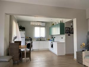 uma cozinha com armários brancos e uma mesa num quarto em Faros Beach sea view apart em Pafos