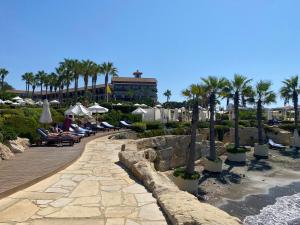 un complejo con palmeras y gente sentada en sillas en Faros Beach sea view apart, en Pafos