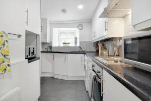 a white kitchen with white cabinets and a window at Frenchgate Holiday Stay in Richmond