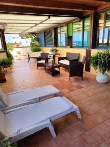 un patio con 2 camas, sillas y mesas en "Appartamento del Mare Gliaca" con vista Isole Eolie,ampia terrazza,wifi e parcheggio gratuito, en Piraino