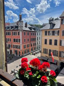 een balkon met uitzicht op een stad met rode bloemen bij Le Chalet de l'Horloge in Chambéry