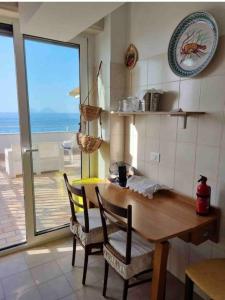 a kitchen with a table and chairs with a view of the ocean at Attico una finestra sulle Isole Eolie in Brolo