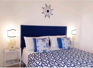a bedroom with a bed with a blue headboard and a clock at Attico una finestra sulle Isole Eolie in Brolo