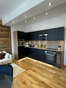 een grote keuken met zwarte kasten en een houten vloer bij Le Chalet de l'Horloge in Chambéry