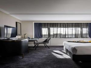 a hotel room with a bed and a desk at Pullman Auckland Hotel & Apartments in Auckland