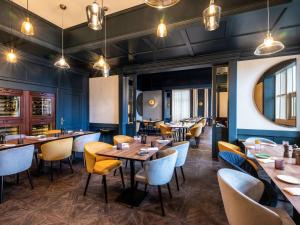 a restaurant with wooden tables and yellow chairs at Pullman Stuttgart Fontana in Stuttgart