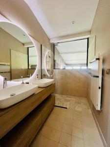 ein Badezimmer mit zwei Waschbecken und einem großen Spiegel in der Unterkunft La Demeure du Val (piscine, hammam, spa, salle de sport) in Couzon-au-Mont-dʼOr