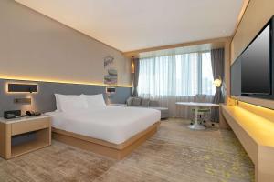 a hotel room with a large bed and a television at Hilton Garden Inn Foshan in Foshan