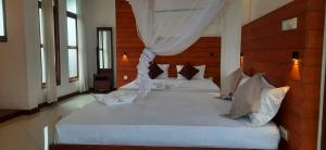 a bedroom with a large white bed with a wooden headboard at White Block Hotel & Resturant in Hatton