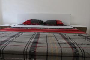 a bed with a plaid blanket and two pillows at Cozy Apartment in Skopje in Skopje