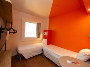 Duas camas num quarto com uma parede laranja em ibis budget Recife Jaboatão no Recife