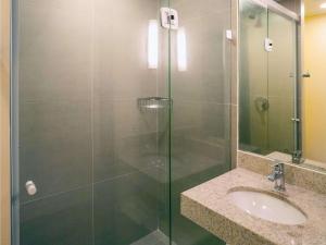 a shower with a glass door next to a sink at ibis budget Recife Jaboatão in Recife