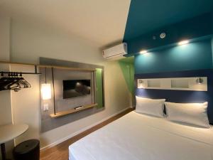 a bedroom with a bed and a tv on the wall at ibis budget Recife Jaboatão in Recife