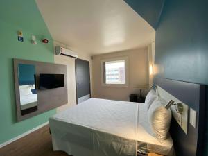 a bedroom with a white bed and a window at ibis budget Recife Jaboatão in Recife