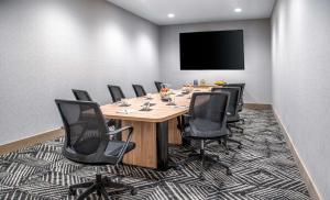 uma sala de conferências com uma grande mesa de madeira e cadeiras pretas em Hyatt Place Newark-Silicon Valley em Newark
