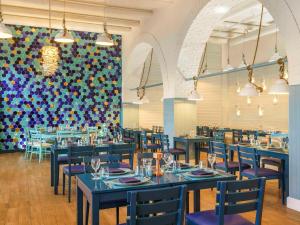 a restaurant with blue tables and chairs and a colorful wall at Rixos Bab Al Bahr - Ultra All Inclusive in Ras al Khaimah