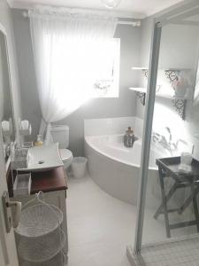 Baño blanco con bañera y lavamanos en C the Sea 3bedroom house with 2 queen and 2 single beds max 6sleep 2bathroom walk distance to beach in Glentana Outeniqua Strand with free Wi-Fi and sea view, en Outeniqua Strand