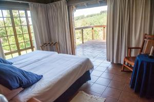 a bedroom with a bed and a balcony at Cheerio Trout Fishing & Holiday Resort in Haenertsburg