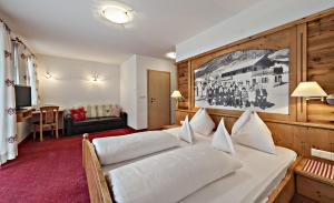- une chambre avec un grand lit blanc dans l'établissement Hotel Pfandleralm, à San Martino