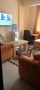 een woonkamer met een tafel en een flatscreen-tv bij TRANGQUIL APARTMENTS in Kitengela 