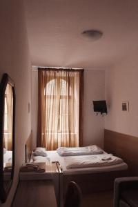 a bedroom with two beds and a mirror and a window at Hotel Amphone in Brno