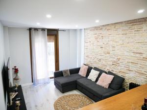 ein Wohnzimmer mit einer Couch und einer Ziegelwand in der Unterkunft Espacioso apartamento en el centro de Pamplona in Pamplona