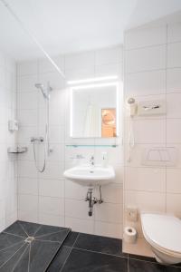 a white bathroom with a sink and a toilet at 4-Länder-Hotel Deutschmann in Bregenz +37 photos
