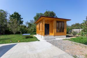 a small wooden cabin with a bench in a park at Cosy Kvara77 in Zugdidi